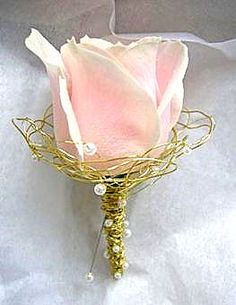 a single pink rose with pearls and gold wire wrapped around it, sitting on a white sheet