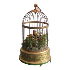 a bird in a cage filled with flowers and greenery on top of a table