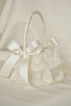 a white lace bag with a bow on the front and ribbon at the bottom, sitting on a bed