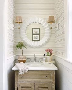 a white sink sitting under a mirror in a bathroom next to a wooden cabinet and two lamps