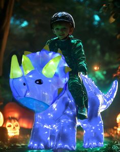 a young boy riding on the back of a blue dinosaur inflatable light sculpture