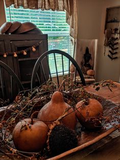 a wooden bowl filled with gourds on top of a table next to a window