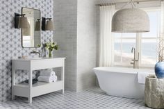 a white bath tub sitting next to a bathroom sink under a large window with blue and white wallpaper