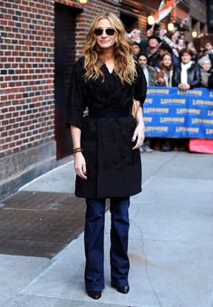 a woman standing on the sidewalk in front of a crowd