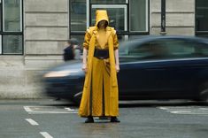 a person in a yellow raincoat is standing on the street