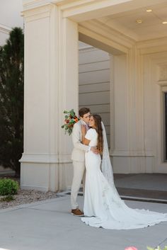 a bride and groom standing in front of a building