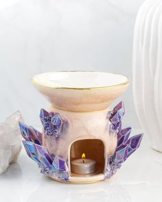 a ceramic candle holder with an open fire place in front of it on a white surface