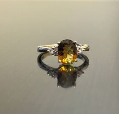 DeKara Designs Collection Our latest design! An elegant and lustrous Golden Tourmaline Diamond Engagement Ring. Metal- 14K White Gold, .583. Stones- Oval Natural Golden Yellow Tourmaline 1.58 Carats, 6 Round Diamonds H-I Color SI1 Clarity 0.24 Carats. Latest of my creations. A Beautiful Unique Colored Tourmaline Diamond Ring. The tourmaline is oval in shape and professionally prong set in between four prongs. There are three prong set round diamonds on each side of tourmaline. There is a beautif Modern Tourmaline Wedding Rings, Wedding Tourmaline Gemstones, Anniversary Sapphire Ring With Tourmaline Gemstone Accents, Anniversary Sapphire Ring With Tourmaline Accents, Tourmaline Sapphire Multi-stone Wedding Ring, Wedding Multi-stone Sapphire Tourmaline Ring, Multi-stone Tourmaline Sapphire Ring For Wedding, Oval Tourmaline Gemstones For Wedding, Wedding Oval Tourmaline Gemstones