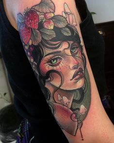 a woman's face with flowers and berries on her head is shown in this tattoo design