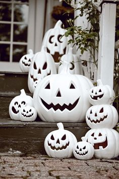 halloween pumpkins are sitting on the steps in front of a house, with faces carved into them