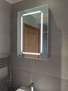 a bathroom with a sink, mirror and towel dispenser on the wall