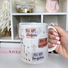 a person holding a coffee mug in front of a shelf with other items on it