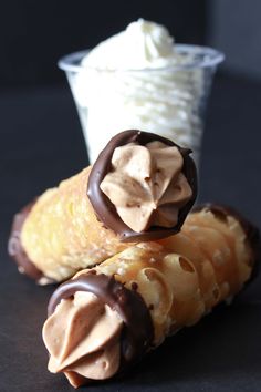 two pieces of chocolate covered pastry next to a cup