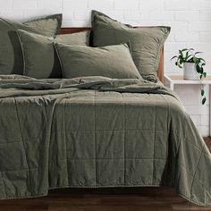 a bed with green sheets and pillows on it