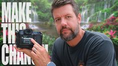 a man holding up a camera with the words make the change in front of him