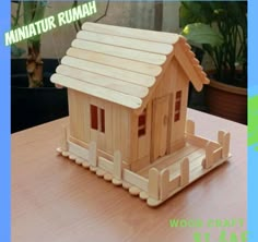 a small wooden house sitting on top of a table next to a potted plant