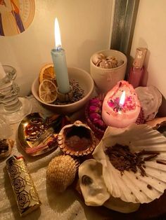 an assortment of seashells, candles and other items are on the table next to each other