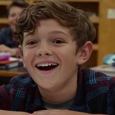 a young boy smiles while sitting at a desk