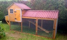 a chicken coop with a red roof and a pink tin roof on the side of it