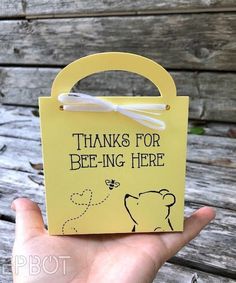 a hand holding a yellow paper bag that says thanks for bee - ing here