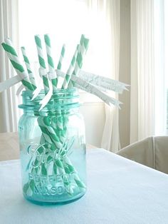 there are many green and white striped straws in a mason jar on the table