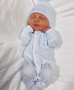 a baby is laying down wearing a blue striped onesie and holding his head up