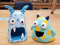 two toys sitting on top of a wooden table next to each other in the shape of monsters