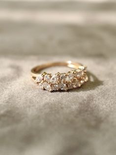 a gold ring with three stones on it sitting on top of a bed sheet in the sunlight