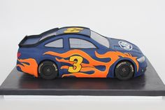 a toy car with flames painted on it's body sitting on a black stand