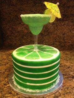 a green cake with a lemon slice on top and a small umbrella sticking out of it