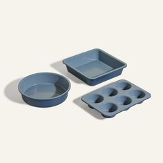 an assortment of blue bowls and pans on a white surface with one empty cup