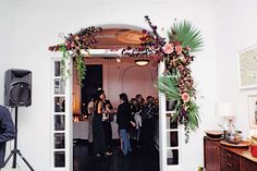 a group of people standing in front of a doorway with flowers on the door frame