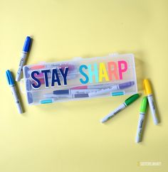 several markers and pens in a plastic container with the word stay sharp written on it