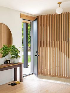 an entryway with wooden slatted doors and a plant on the side table