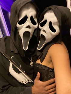 two people in masks hugging each other with one holding the other's arm around his shoulder