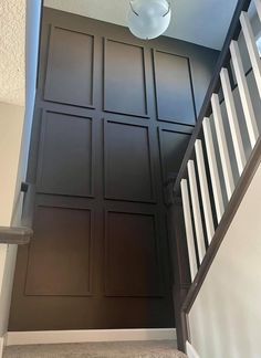 an open door leading to a hallway with dark wood paneling and white railings