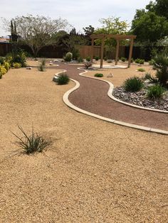 a garden with gravel paths and plants in the center, surrounded by shrubs and trees