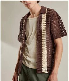 a young man wearing a brown and white crochet cardigan with his hands in his pockets