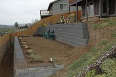 a dog standing on the side of a house next to a fenced in yard