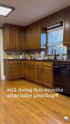 a kitchen with wooden cabinets and a black dishwasher in the middle is shown