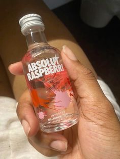 a person holding a bottle of absolu raspberry water in their hand