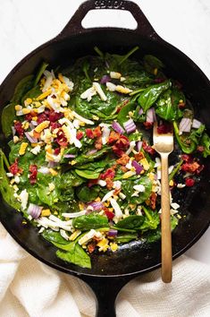 spinach salad in a skillet with a wooden spoon