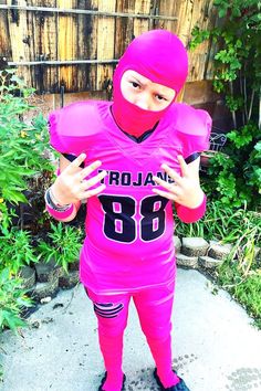 a person in a pink football uniform holding their hands up to the camera while standing outside