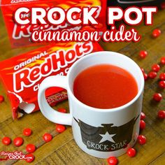 a cup of crock pot cinnamon cider sits next to a box of candy