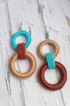 two pairs of knitted hoop earrings on top of a white wooden table with wood beads