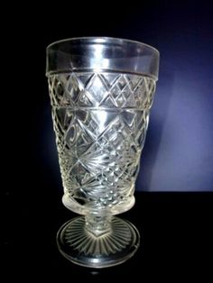 a clear glass cup sitting on top of a black table next to a blue wall