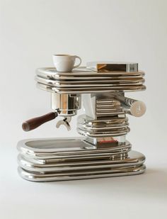 an espresso machine sitting on top of a stack of silver plates and cups