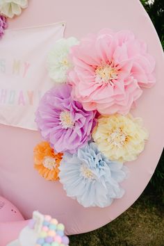 there are many flowers on top of the pink tablecloths and cake in front of it