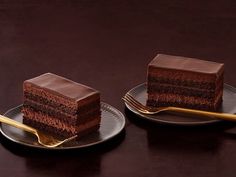 two slices of chocolate cake on plates with gold forks