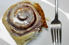 a cinnamon roll sitting on top of a white plate next to a fork